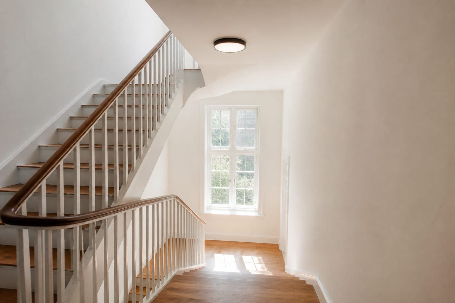Helles saniertes Treppenhaus mit neuen Deckenleuchten und Tageslicht